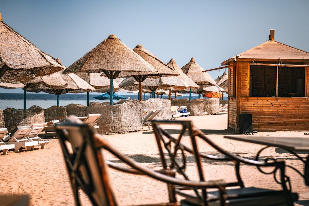 Sunny sandy beach with clear blue water and wooden sun loungers