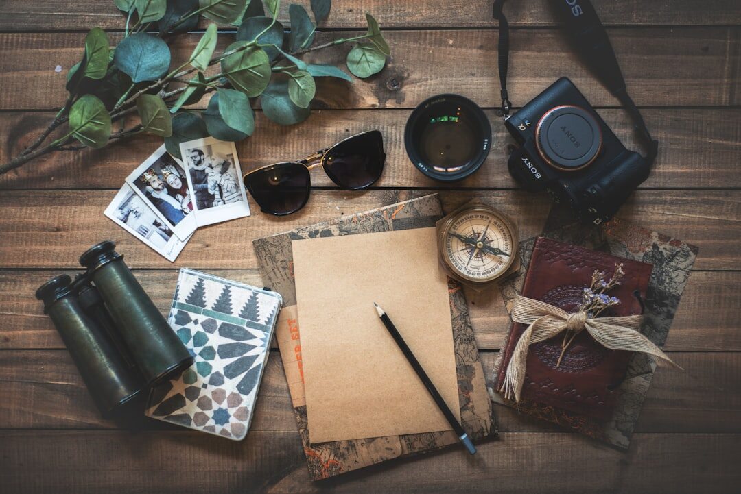 Flat lay of a travel notebook, camera and map of Portugal on a wooden desk