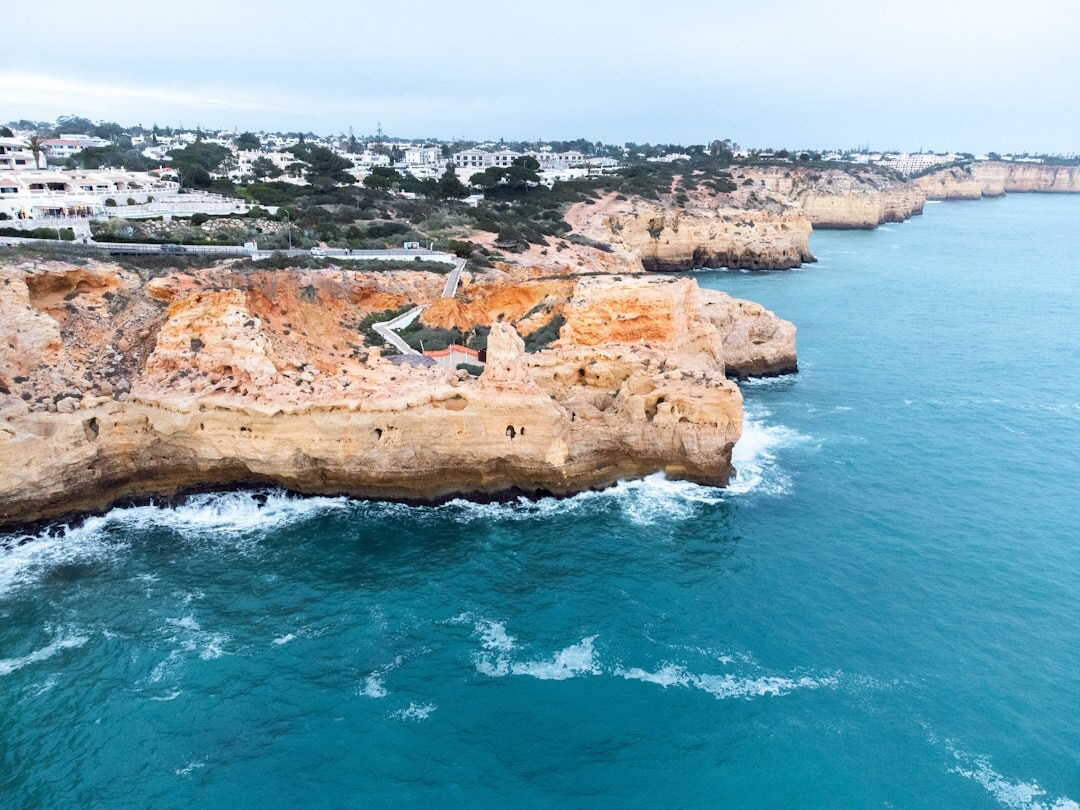 Aerial view of dramatic golden cliffs and turquoise ocean along the Algarve coast in Portugal